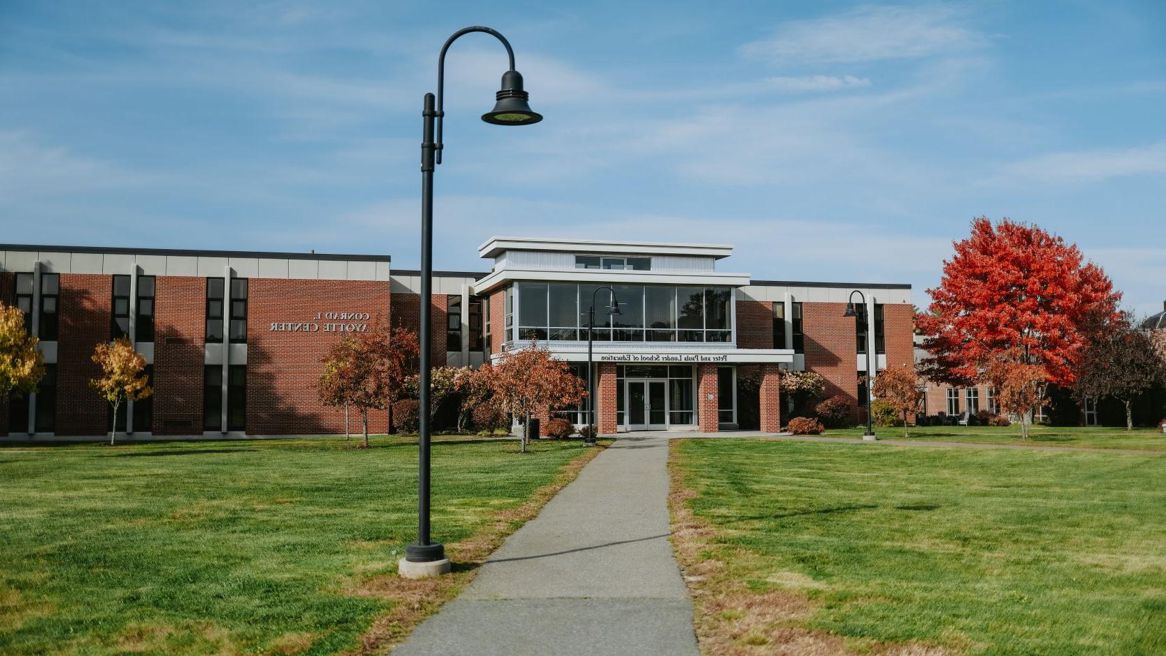 Grass-lined walkway and lightpole in the foreground; large brick building in the background.